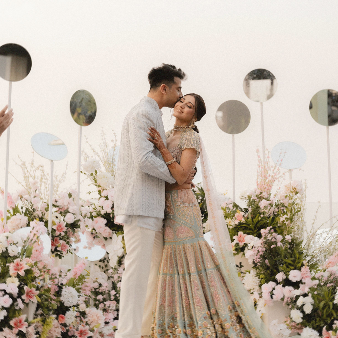 A bride and groom embracing in front of a floral backdrop