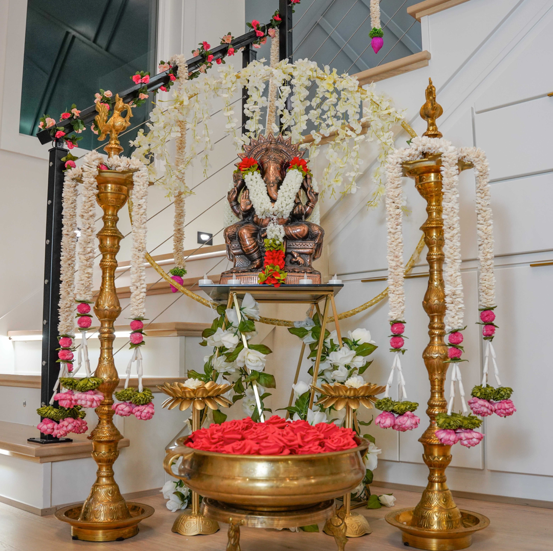 A Ganesha altar with brass lamps and marigold garlands set up for a wedding ceremony